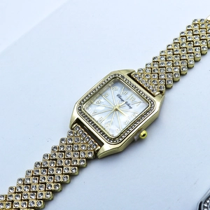 Détail macro de la montre carrée dorée avec strass et cadran en nacre scintillante
