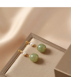 Detail of vintage gold earrings with green jade beads and white freshwater pearls