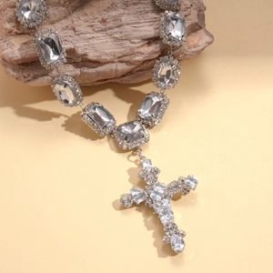 Detailed macro view of a silver rhinestone-encrusted cross pendant on a refined luxury necklace