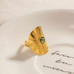 Vintage gold sunflower ring with green turquoise stone on a decorative ceramic plate
