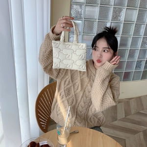 Close-up of quilted cream tote bag featuring cute cartoon rabbit embroidery and soft handle