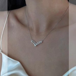 Detail of V-shaped pearl necklace with sparkling zircons on a model's collarbone