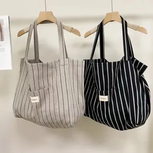 Detail view of large canvas tote bags with contrast stripes and Bonogeed front pocket