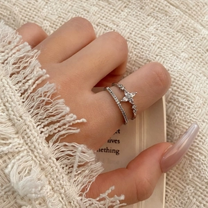 Close-up of stacked silver rings with star motifs and crystals on a model's finger