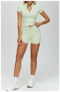 Detail of mint green yoga set featuring half-zip short sleeve top and high waist shorts
