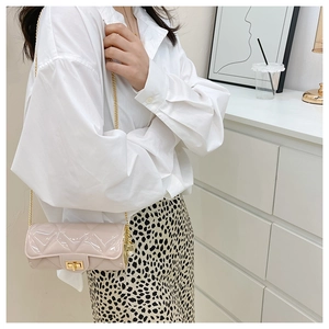 Close-up of pink quilted cylindrical barrel bag with gold chain strap and turn lock