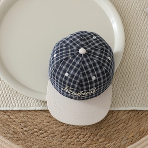 Close-up of checkered kids baseball cap with Kindness embroidery and beige flat brim