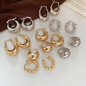 Close-up of assorted gold and silver C-shaped metal earrings in various textures