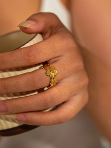 Detailed view of a gold floral eternity ring worn on finger with vintage matte texture