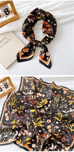 Detailed view of floral silk scarf featuring orange blossoms and striped border texture