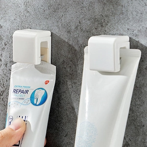 Gros plan de deux presse-dentifrice muraux en plastique blanc sur un mur en pierre grise