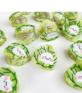 Flat lay of multiple cute cabbage-shaped acetic acid hair clips with cartoon faces