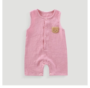 Detail of pink gauze baby romper featuring a cute brown 3D bear patch and snap buttons