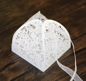 Close-up of laser-cut rose hollow candy box in white with silk ribbon detail