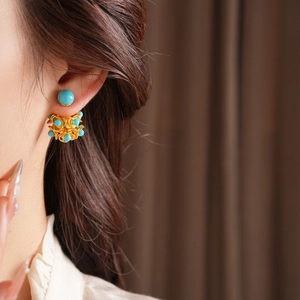 Gros plan détaillé d'une boucle d'oreille lion dansant doré avec perles turquoise