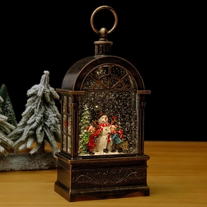 Close-up of vintage bronze Christmas lantern with children building a snowman scene