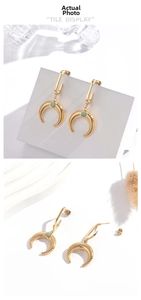 Detail of gold crescent horn earrings with green stone inlay and fine textured finish