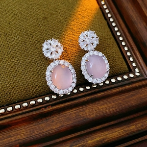 Détails de boucles d'oreilles vintage en calcédoine rose avec zircons sur tissu vert