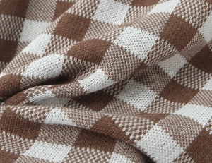 Detailaufnahme der braun-weißen Strickstruktur mit Schachbrettmuster und weichem Stoff