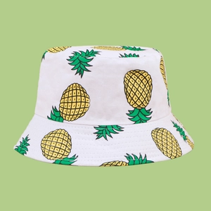 Detail of white cotton sun hat with yellow pineapple pattern and green leaves