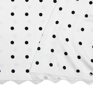 Dettaglio del tessuto in raso bianco a pois con bordo in pizzo sull'orlo del vestito