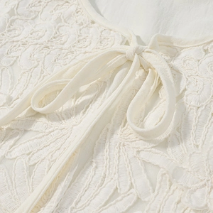 Dettaglio del ricamo in pizzo bianco con un delicato fiocco sullo scollo