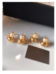 Détail de boucles d'oreilles gourde dorées avec perles et incrustations de zircons