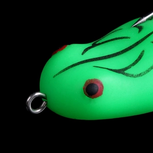 Macro shot of green soft frog lure head with realistic eyes and silver metal ring