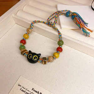 Detail of handmade ceramic bead bracelet with colorful woven cord and black cat pendant