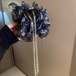 Détail d'une pince à cheveux en mousseline noire avec longs pompons argentés