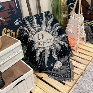 Close-up of bohemian woven blanket featuring celestial sun and moon patterns with tassels