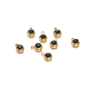 Détail de breloques rondes de 6mm en acier inoxydable doré avec zircons noirs sur fond blanc