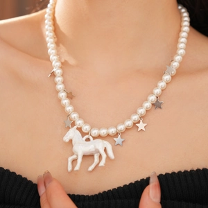 Detail of beaded pearl necklace featuring silver stars and white horse pendant on model