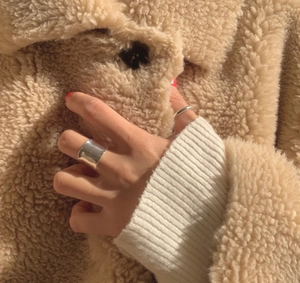 Close-up of a minimalist silver band ring set worn against a soft beige texture background