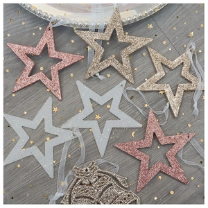 Close-up of pink, gold and silver glitter Christmas star and bell ornaments on mesh background