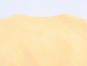 Dettaglio di una giacca in tweed giallo pallido con scollo rotondo e trama del tessuto