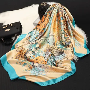 Retro floral satin square scarf in blue and yellow draped on a soft plush background