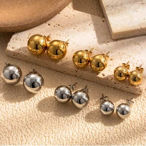 Polished titanium steel ball stud earrings in gold and silver set on travertine stone