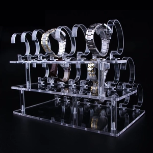 Three-tier transparent acrylic watch stand with detachable C-ring holders on dark background
