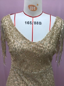 Dettaglio dell'abito a sirena con paillettes dorate, scollo a V e rifiniture con frange