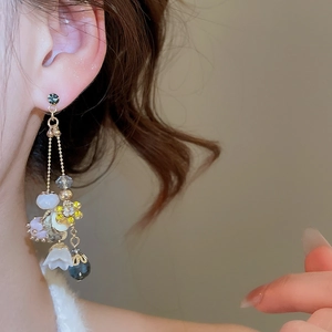 Close-up of elegant floral drop earrings with gold chains and crystal beads on a model