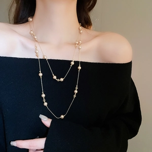 Détail du collier à deux rangs en perles champagne et cristal sur pull noir
