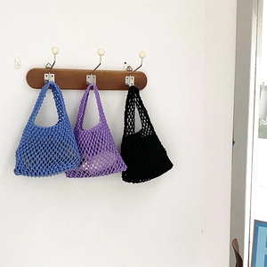 Detail of blue, purple and black handmade cotton rope woven tote bags on wall hooks