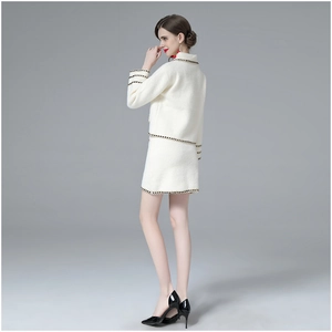 Detail of white knit jacket and skirt showing black and white woven trim and fabric texture