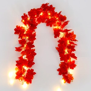 Detail of autumn red maple leaf string lights with warm LED glow on white background