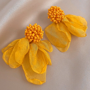 Elegant yellow lace flower stud earrings on beige satin fabric background for women