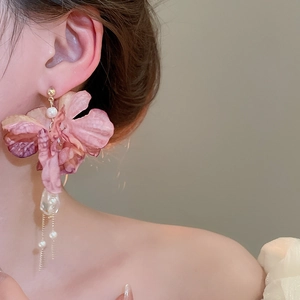 Detail of pink fabric flower earrings with pearls and metal tassels on model