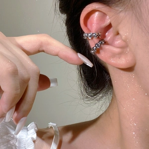 Detail of silver skull ear cuffs stacked on model's ear for a gothic punk aesthetic