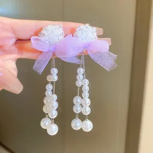 Macro detail of silver tassel earrings with purple mesh butterfly and white pearls