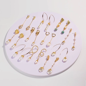 Detail of assorted gold wire-wrapped baroque pearl earrings on a purple display stand